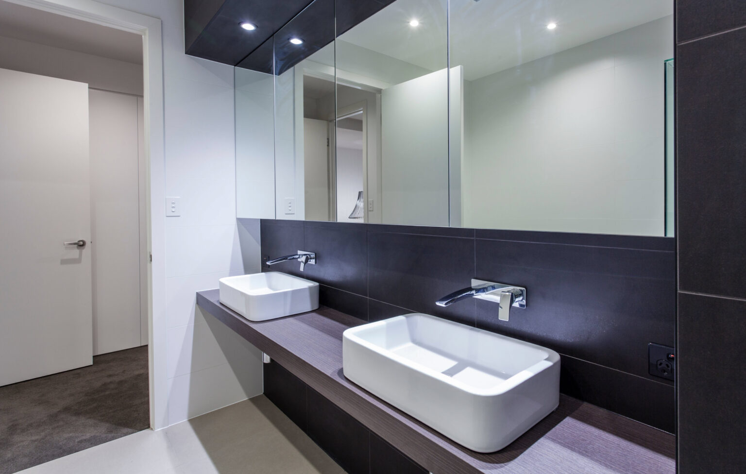 Reforma de baño moderno con doble lavabo y espejo retroiluminado realizada por Greyscos en Barcelona