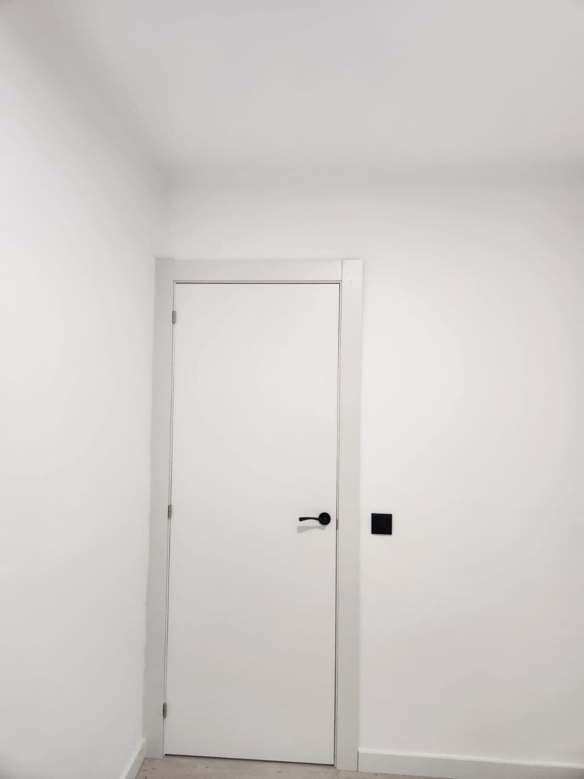 Puerta interior blanca con maneta negra instalada en piso reformado en Barcelona