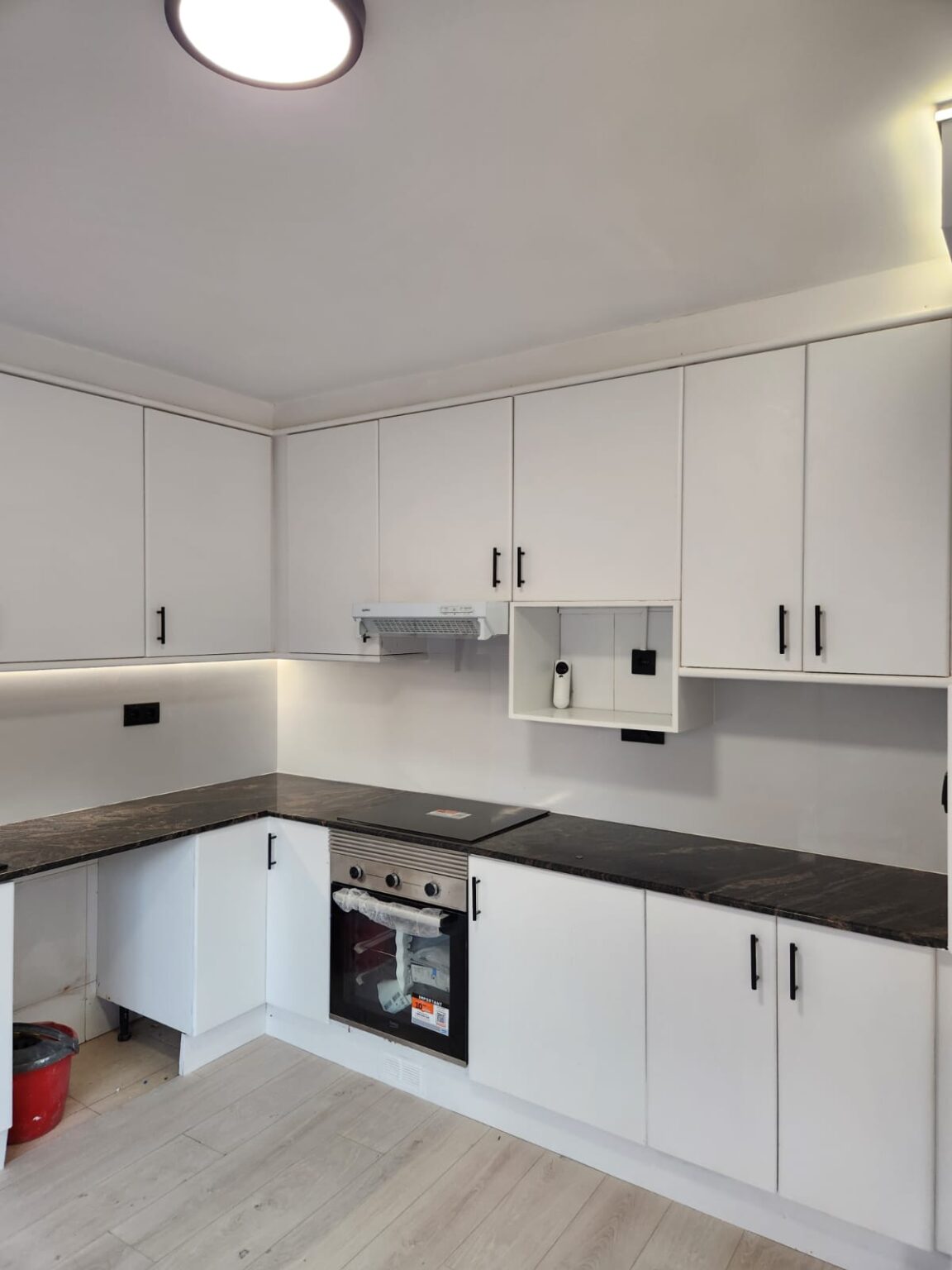 Cocina en L con horno integrado y muebles blancos instalada durante reforma integral en Barcelona