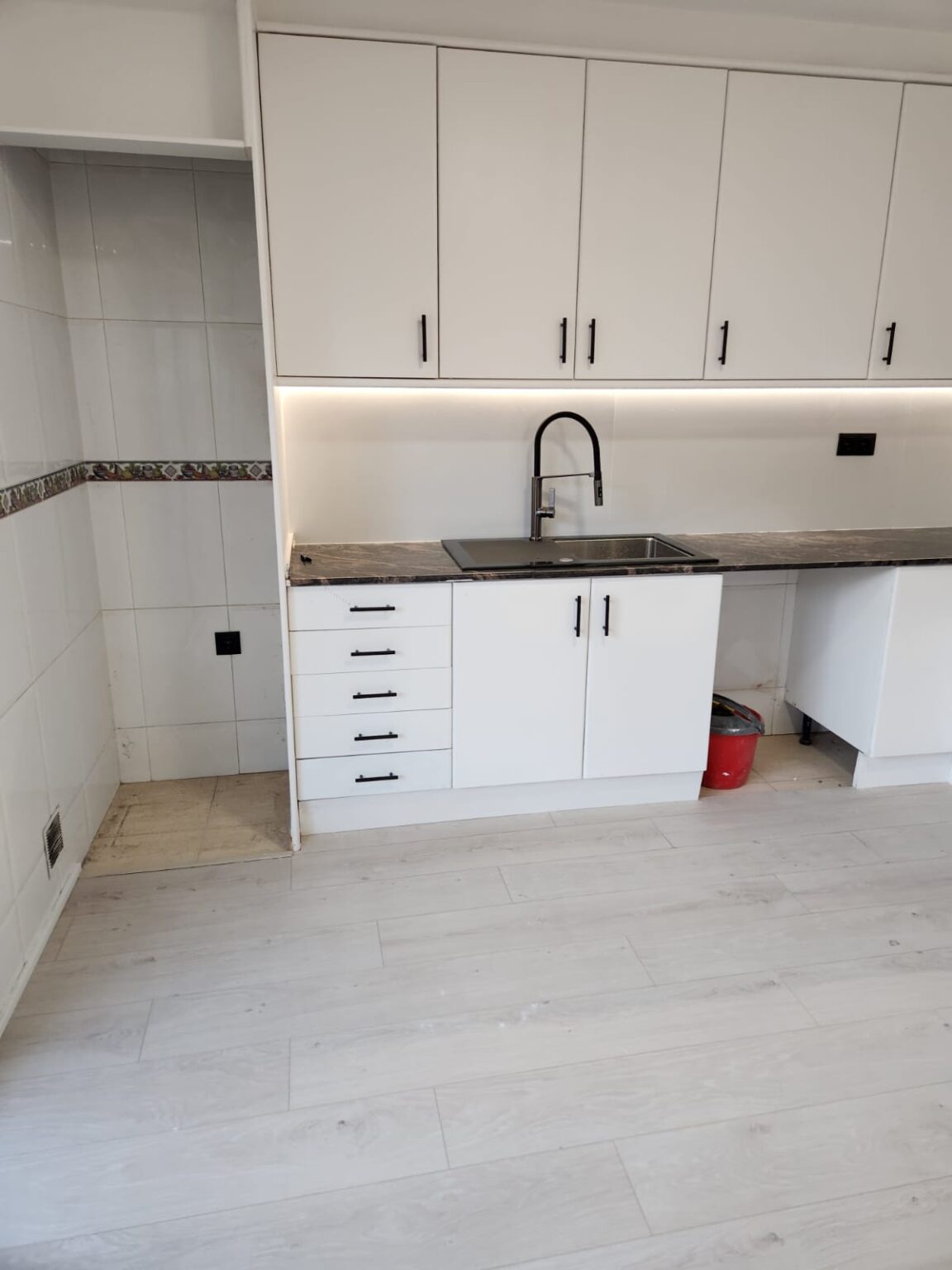 Cocina moderna con fregadero y encimera oscura en vivienda reformada en Barcelona