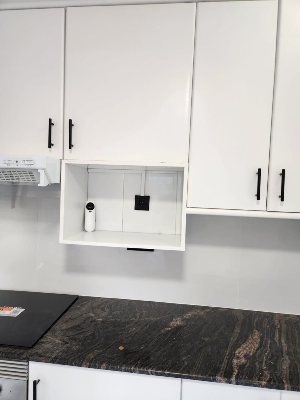 Cocina reformada con muebles blancos y encimera oscura en piso reformado en Barcelona