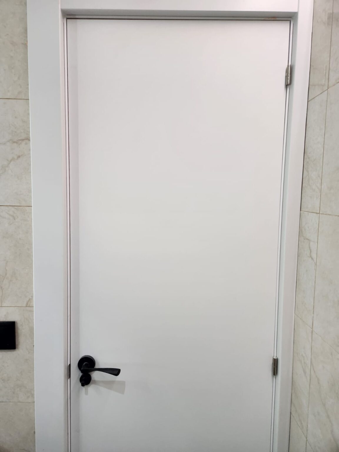 Puerta interior blanca con maneta negra en vivienda reformada en Barcelona