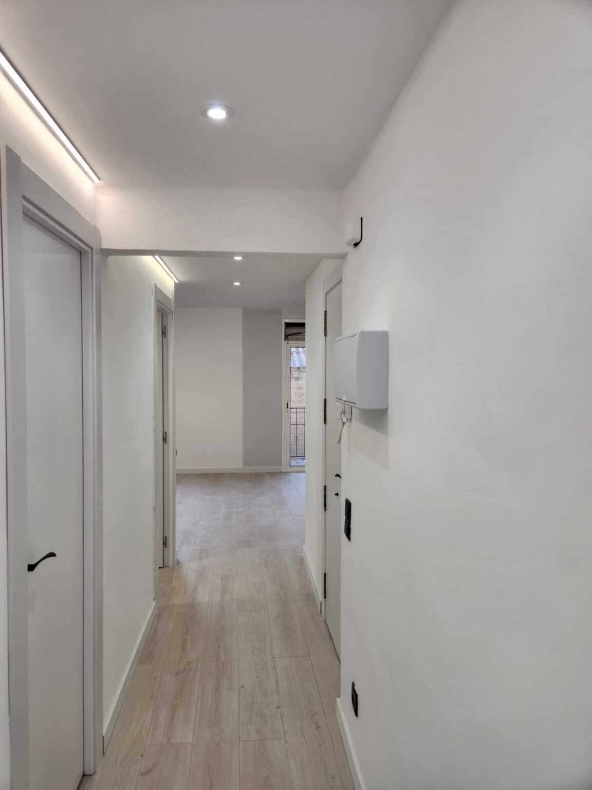 Pasillo largo con iluminación empotrada tras reforma integral de vivienda en Barcelona