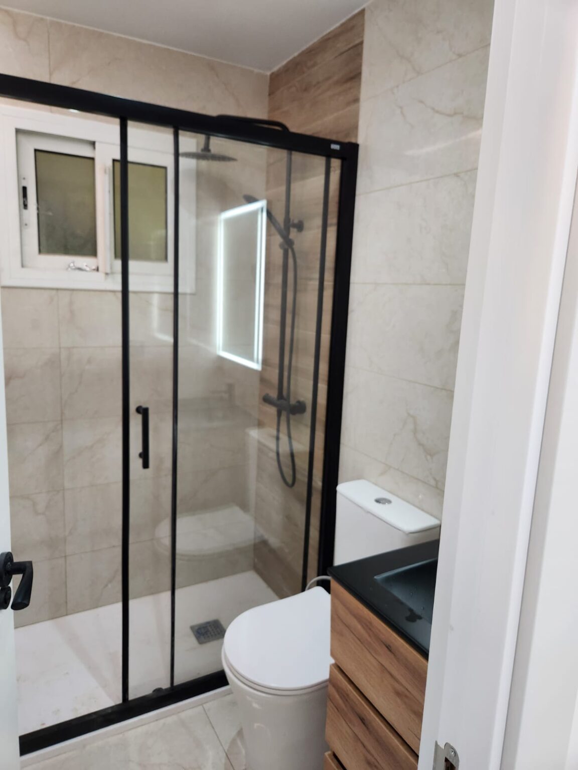 Baño reformado con ducha de cristal y lavabo moderno en vivienda de Barcelona