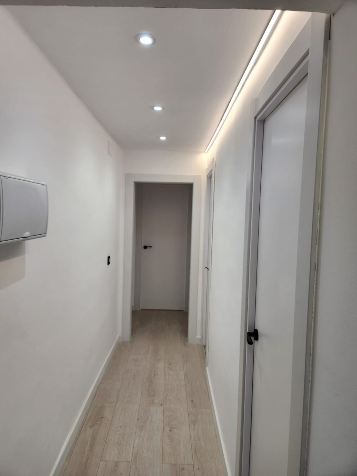 Pasillo de piso reformado con iluminación LED y suelo moderno en Barcelona